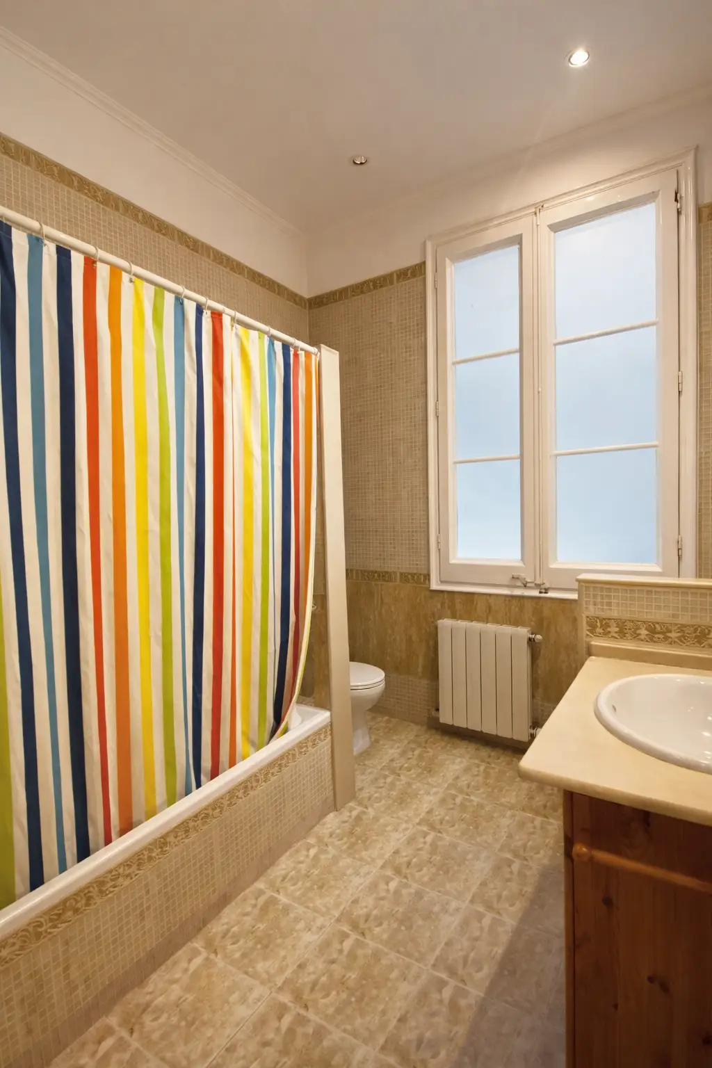 Antes de la reforma de baño: bañera con cortina de rayas y gresite beige en Madrid