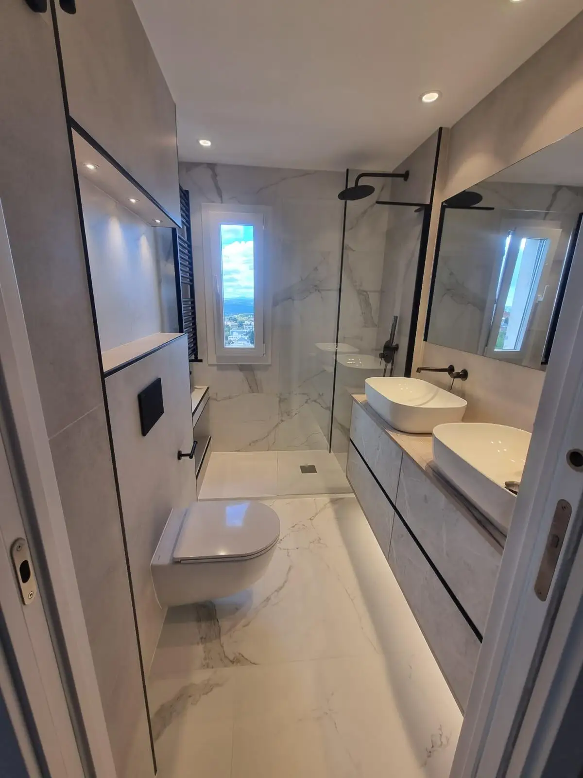 Reforma de baño con lavabo doble sobre encimera y grifería negra empotrada en Madrid
