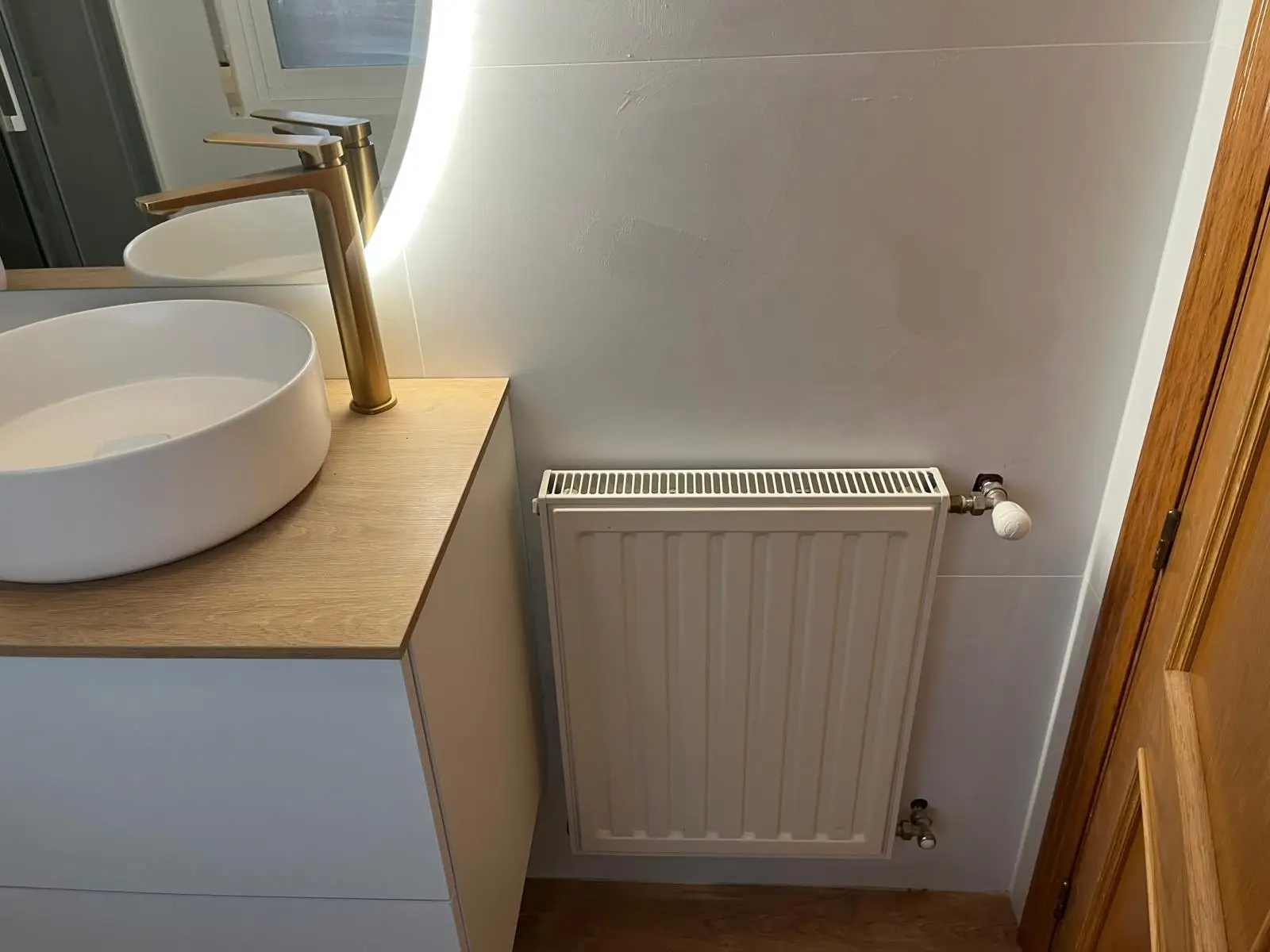 Reforma de baño con lavabo circular sobre encimera de madera y grifería dorada en Madrid