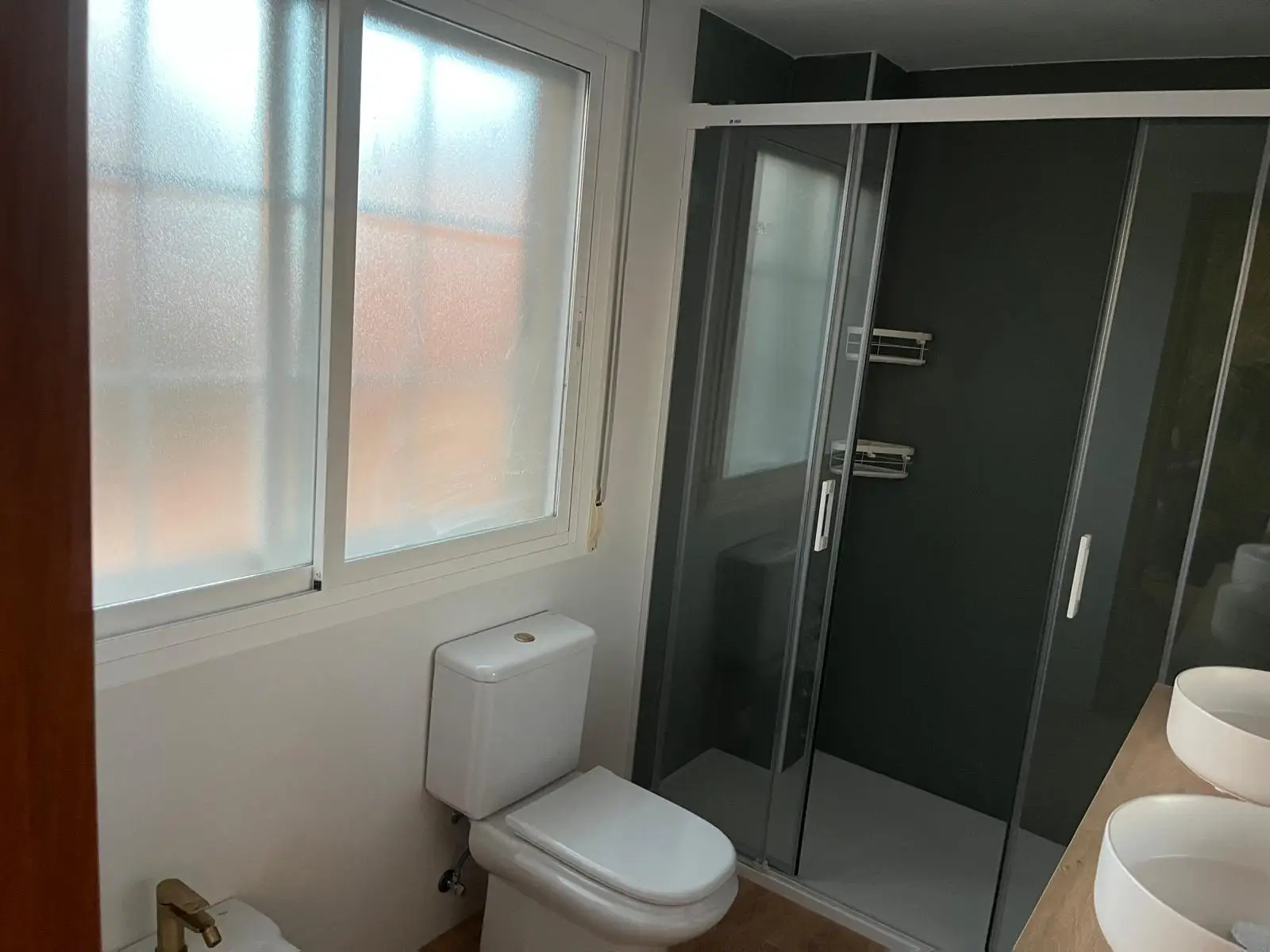 Reforma baño con mampara corredera de perfil blanco y paredes de ducha oscuras en Madrid