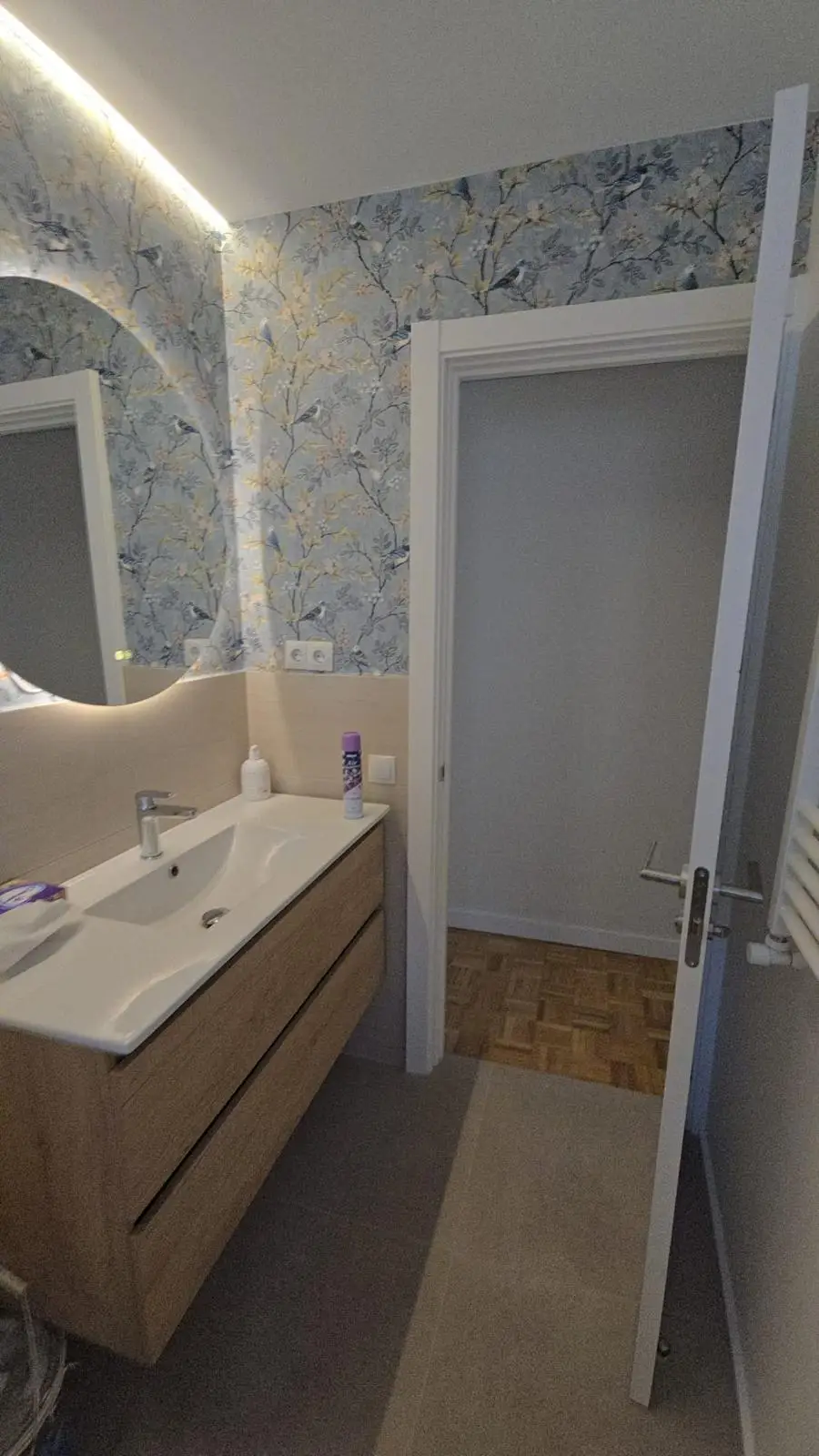 Reforma de baño con papel pintado de motivos florales y pájaros sobre zócalo cerámico en Madrid