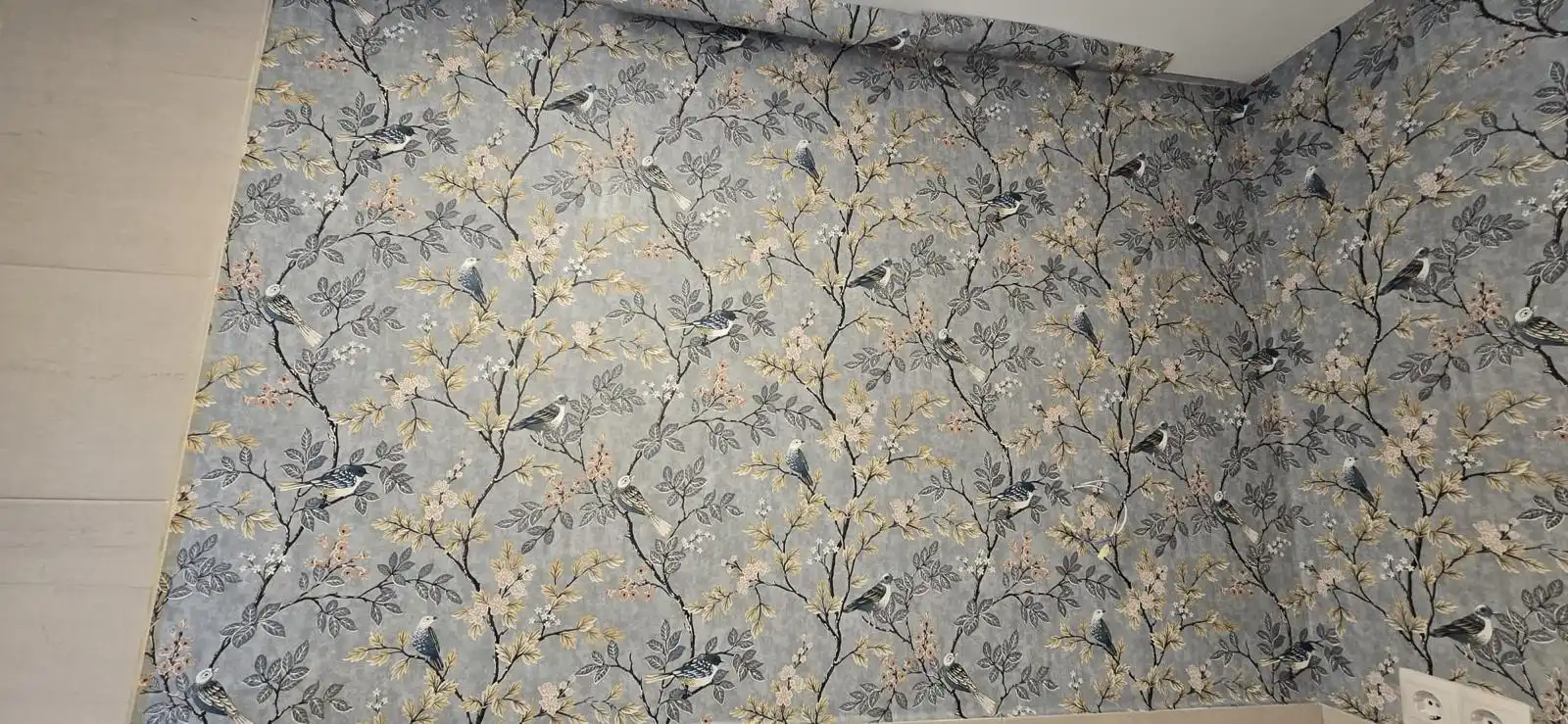 Reforma de baño con papel pintado de motivos florales y pájaros sobre zócalo cerámico en Madrid
